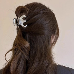 Polished silver metal hair claw clip in pumpkin shape shown on model hair