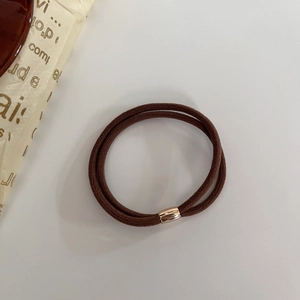 Dettaglio dell'elastico per capelli marrone a doppio filo con perla in oro rosa