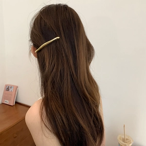 Minimalist gold metal spring hair clip worn on long hair for a sleek modern style
