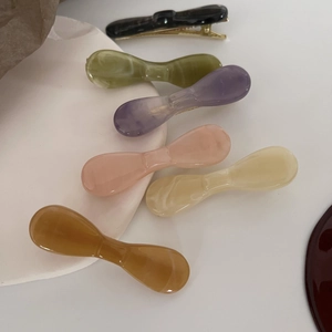 Set of six colorful marble pattern resin hair clips on a white ceramic plate