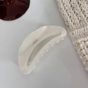 Détail d'une pince à cheveux blanc crème nacré avec l'inscription France Handmade sur gris