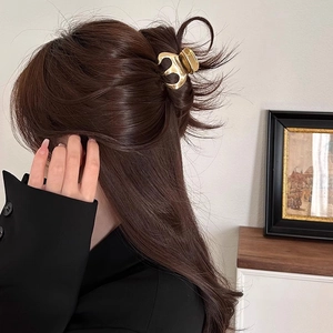 Detailed close-up of a golden pumpkin-shaped metal hair claw used for a stylish updo