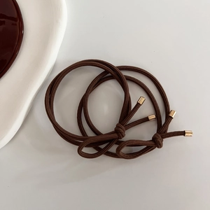Detail of two dark brown high-elastic hair ties with golden metal tips on white background