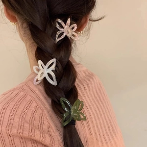 Close-up of acetic acid butterfly hair clips in cream, floral pink, and dark green on hair