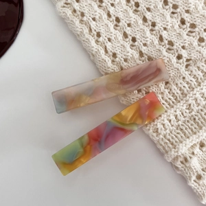 Close-up of rectangle acetate hair claws with marble texture on white knit fabric