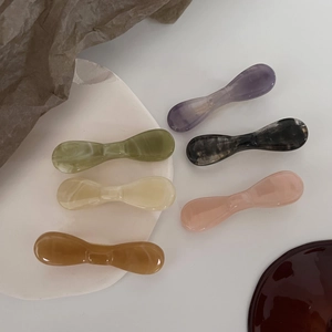 Set of six acetate bow hair clips in marble texture colors displayed on white tray