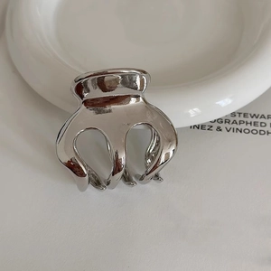 Macro shot of polished silver metal hair claw clip showing glossy finish and texture