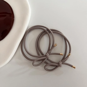 Detailed macro view of two elastic brown hair ties with golden metal cylinders and bows