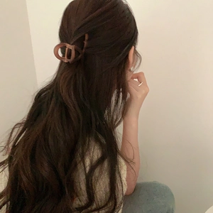 Detail view of a tortoise shell hair claw clip styled on long brown wavy hair