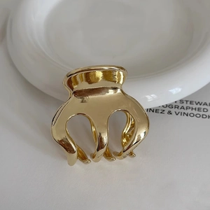 Macro shot of a minimalist gold pumpkin-shaped metal hair claw with polished finish