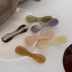 Elegant Korean acetate bow hair clips set in various marble colors on white ceramic tray