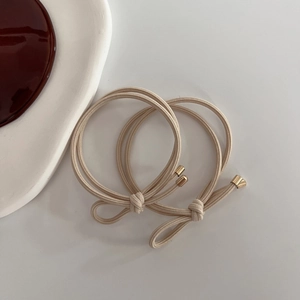Detail of beige elastic hair ties with central bow knot and gold metal ends in 2-pack