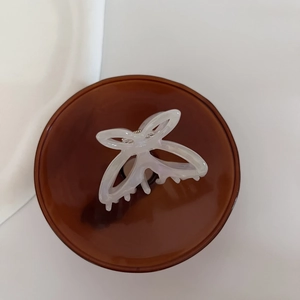 Macro detail of pearlescent white acetate hollow butterfly hair claw clip with fine teeth
