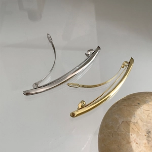 Close-up of minimalist metal spring hair clips with a polished gold and silver mirror finish