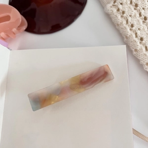 Detail of a large rectangular acetate hair claw clip with colorful marble texture finish