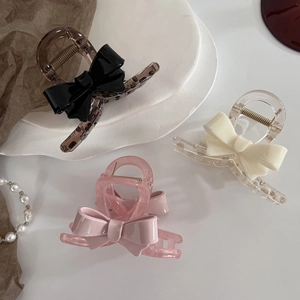 Gros plan de pinces à cheveux à nœud en acrylique en trois couleurs sur une assiette décorative