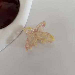 Macro shot of acetic acid butterfly hair clip with pink and yellow gradient texture
