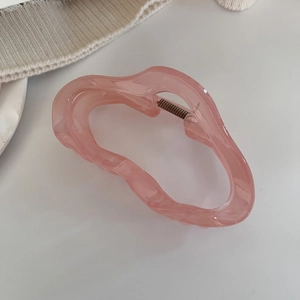 Vue macro de la pince à cheveux rose translucide avec bords ondulés et ressort