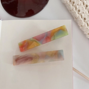 Set of two rectangular hair clips with colorful marble acetate texture on white surface