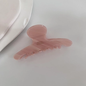 Close-up of pink acetate hair claw clip with marble texture and gold lettering detail