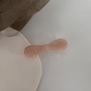 Detailed close-up of pink translucent resin bow hair clip on a white stone base