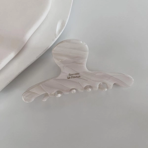 Detail of marbled white acetate hair claw clip featuring golden Barrette La France text