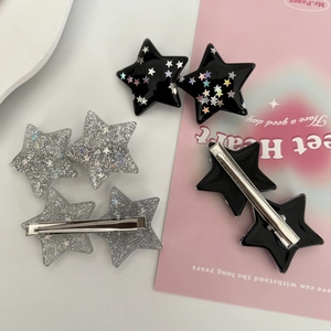 Y2K style black and silver glitter star hair claws for women displayed on a pink background