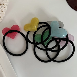 Detailed view of seven colorful translucent resin heart hair ties on a white lace background
