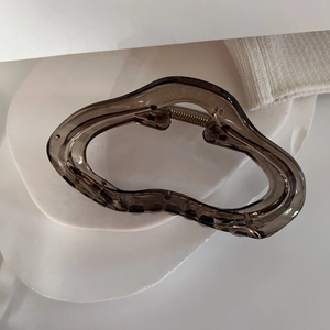 Détail de la pince à cheveux ondulée marron foncé translucide avec ressort en métal doré