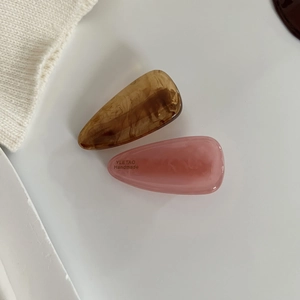 Elegant amber and pink marble acetate teardrop hair clips with handmade engraving on white background
