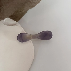 Detailed view of a purple marble resin hair clip on a minimalist white stone base