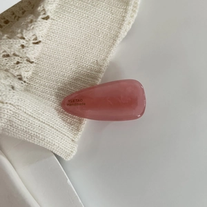 Detail of pink marble textured acetate teardrop hair clip with handmade logo engraving