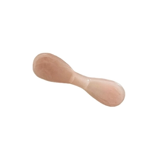 Pink translucent resin facial massage tool with smooth finish on white background
