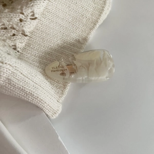 Close-up of cream acetate hair clip with marble texture and gold handmade lettering