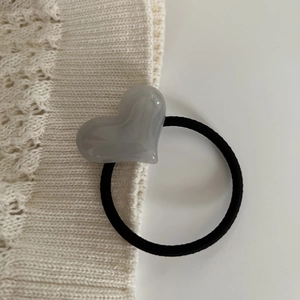 Detail of high-elasticity black hair tie with polished gray heart resin accessory
