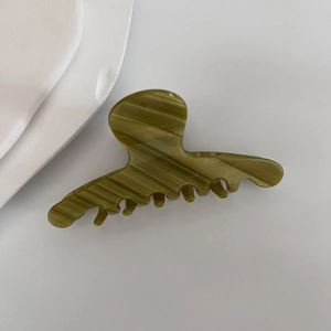 Detail of elegant olive green marble texture acetate hair claw clip with glossy finish