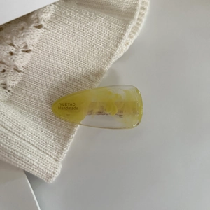 Detailed macro view of the handmade amber acetate hair clip on soft white knit fabric