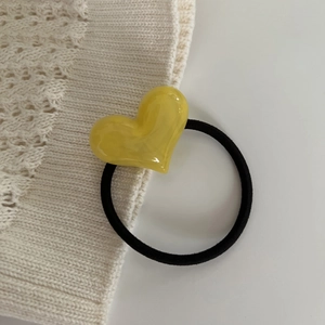 Close-up of durable black elastic hair tie with a glossy yellow heart-shaped resin bead