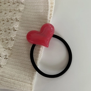 Close-up of a pink marbled resin heart pendant on a black elastic hair tie for women