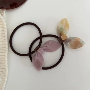 Detailed macro view of purple and amber rabbit ear charms with handmade lettering on hair ties