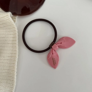 Close-up of a pink high-elastic rabbit ear hair tie with a gold handmade label