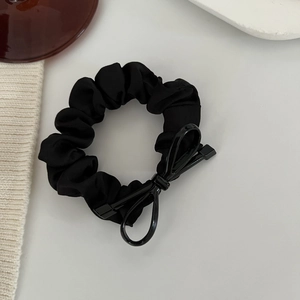 Dettaglio di un elegante elastico in raso nero con fiocco lucido su fondo bianco