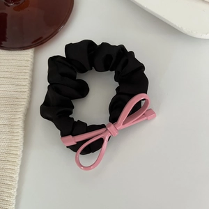Dettaglio di un elastico in raso nero con fiocco decorativo in metallo rosa