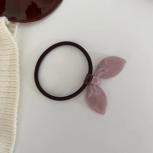 Detail shot of a pink acrylic leaf charm on high-elasticity hair tie with handmade gold label