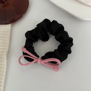 Dettaglio di un elastico in raso nero a pieghe con un fiocco in resina rosa acceso