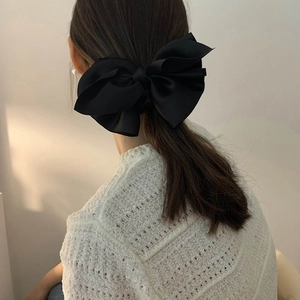 Elegant large black satin bow hair clip shown on the back of a model for styling