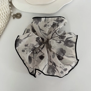 Détail d'un grand chouchou de style français avec imprimé floral gris et bords noirs