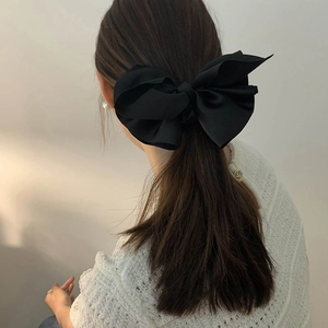 Elegant large black satin bow hair tie with silky texture shown on a ponytail hairstyle