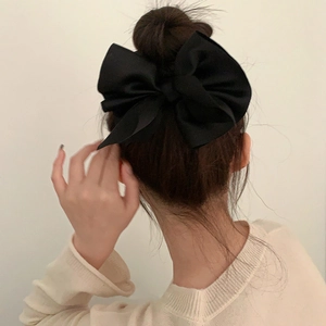 Close-up of a large black satin bow scrunchie on a bun hairstyle for an elegant look