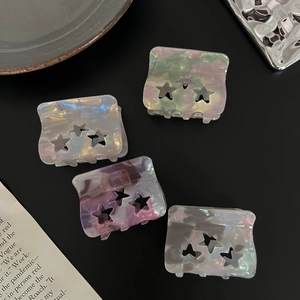 Close-up of four translucent acetate star hair claws with pearlescent mica texture